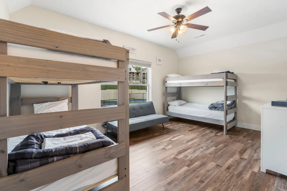 A casual, family-friendly bunk room with bunk beds, a sofa, and a bright window. The layout is perfect for children's sleepovers or flexible family arrangements, embodying a sense of fun and togetherness.