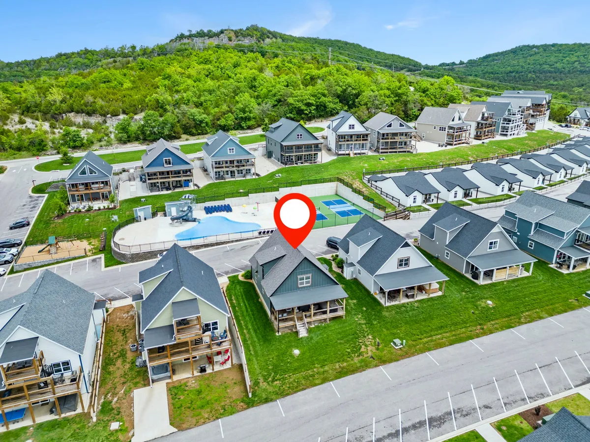 A spacious outdoor swimming pool surrounded by tennis courts and lush greenery, with sunlit water and ample seating for families or groups. The scene radiates summer fun and community activity, ideal for energetic outdoor days.